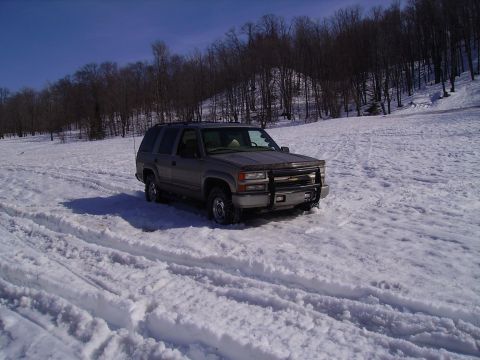 2000 Chevrolet Tahoe - Chevrolet Tahoe navigating a snowy landscape with trees in the background.