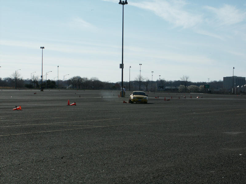 Yellow 2001 Mercury Grand Marquis sedan on a paved lot with orange cones