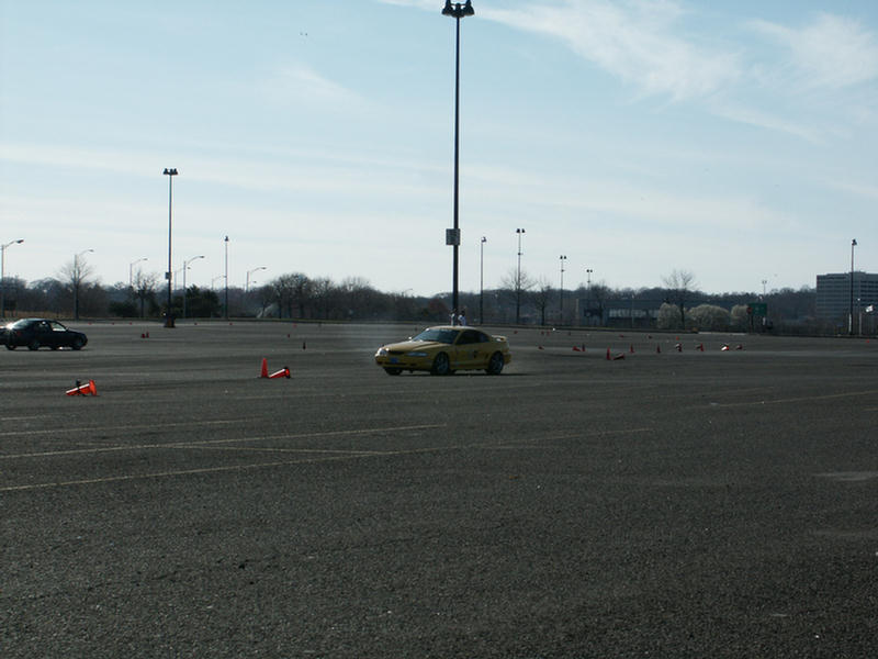Yellow coupe on track with cones