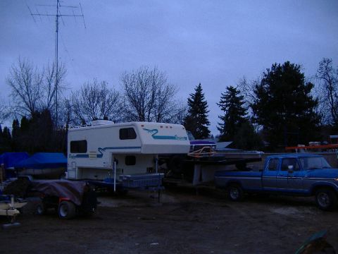 1979 Ford Bronco - A blue pickup truck is parked next to a white camper, with a large antenna in the background.