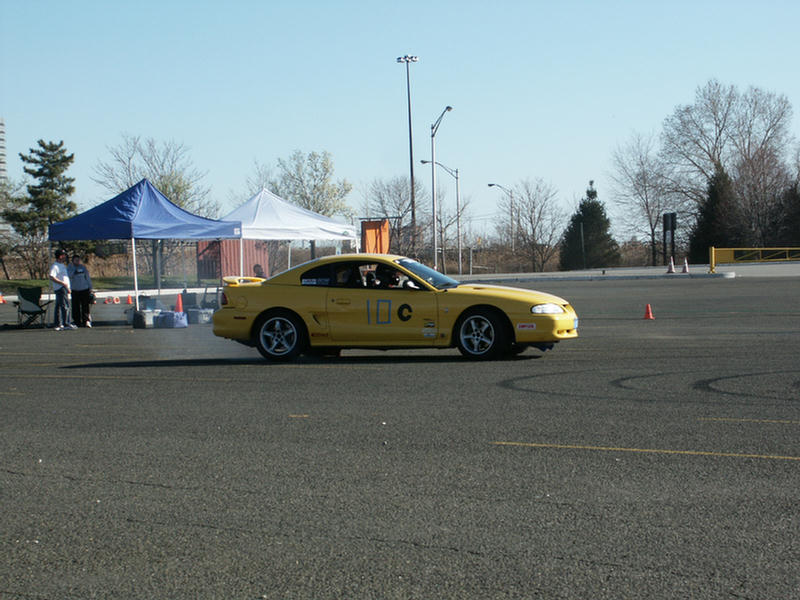 Yellow coupe with racing numbers '10 C' on the door, seen from the side at an auto event