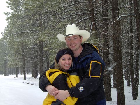 1991 Ford Bronco - A couple embraces in a snowy forest, dressed in warm winter gear.