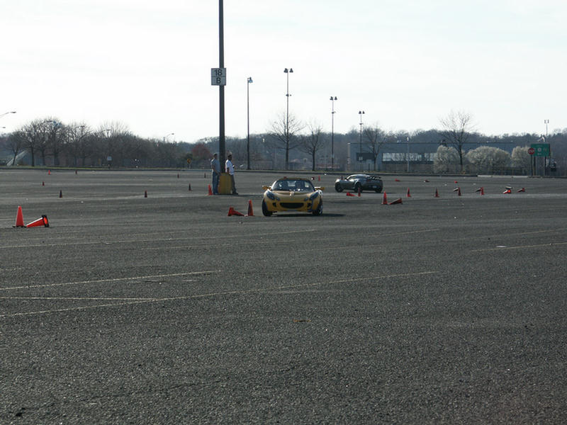 Yellow sports car and black sports car on a paved course with cones