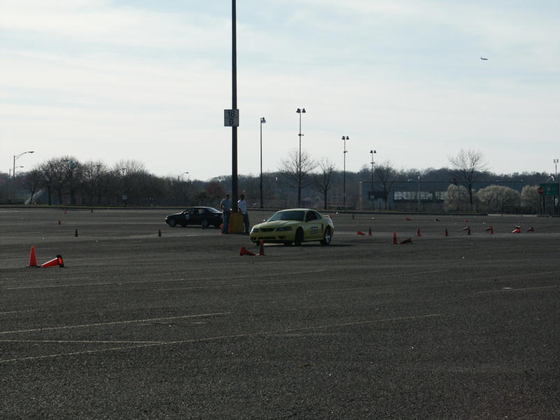 Yellow car on a track with cones, another car in background