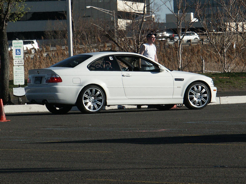 White coupe with racing numbers '6' and 'ava' on the driver's side window, parked on asphalt