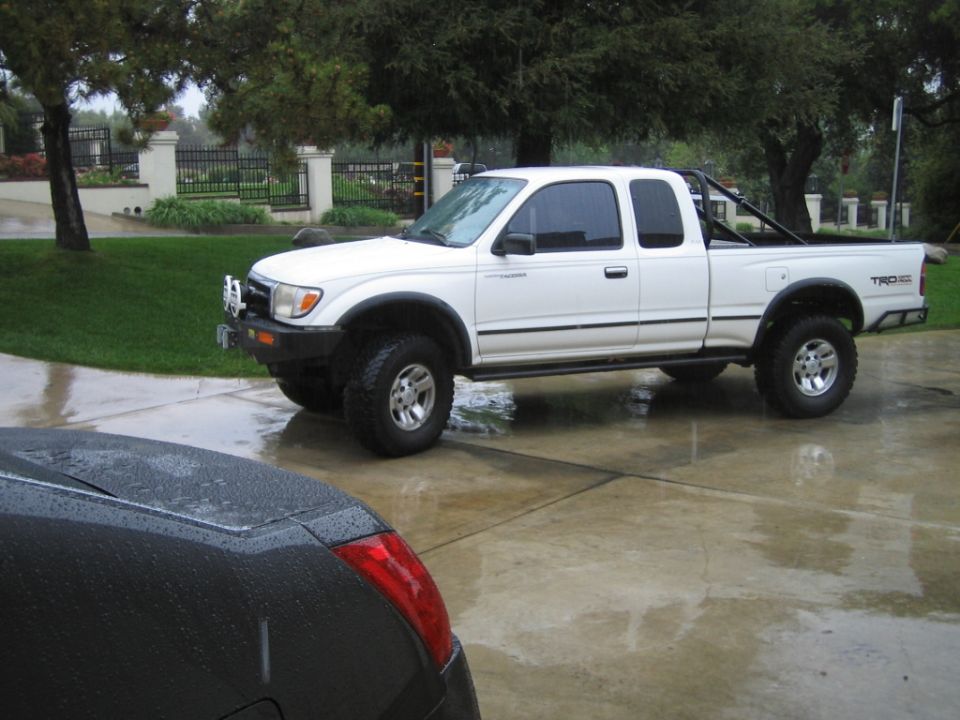 White lifted Toyota Tacoma pickup with winch bumper on wet driveway