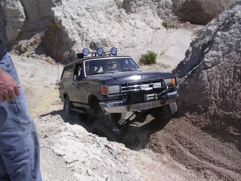 1985 Ford Bronco - This black Ford Bronco navigates a challenging off-road course, its winch and off-road capabilities.