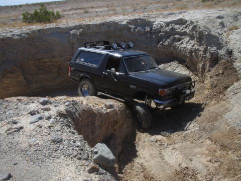 1985 Ford Bronco - This black Ford Bronco is shown off-roading in a dry, rocky ravine.