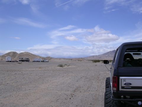 1985 Ford Bronco - A 1985 Ford Bronco is parked in a desert landscape with RVs and mountains visible.