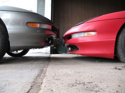 1996 Ford Probe - The front ends of two cars are positioned very close to each other in a garage setting.