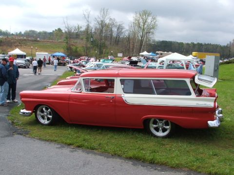 1966 Ford Ranchero - A red and white two-door station wagon with custom wheels is parked on grass at an outdoor car show.