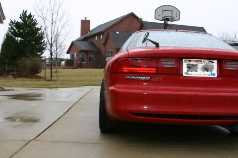 1993 Ford Probe - Rear view of a red 1993 Ford Probe GT on a wet driveway with a house in the background.