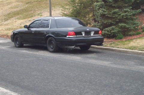 1999 Ford Crown Victoria - Rear view of a black Ford Crown Victoria with aftermarket wheels.