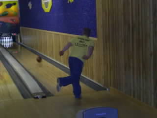 1985 Ford Bronco - A person bowls in a bowling alley with wooden lanes and blue walls.