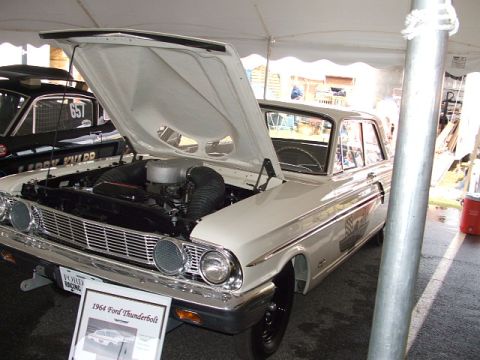 1966 Ford Ranchero - A 1964 Ford Thunderbolt is displayed with its hood open, revealing the engine bay. A police car is visible behind it.
