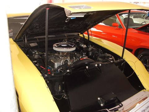 1966 Ford Ranchero - The engine bay of a yellow vehicle is open, revealing its V8 engine and air cleaner assembly.