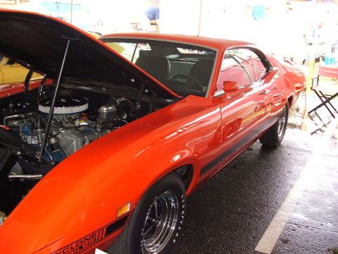 1966 Ford Ranchero - This orange muscle car, identified by its 'CYCLONE GT' badging, is shown from a 3/4 front angle with the hood open to reveal the engine.