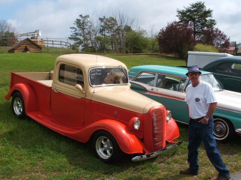 1966 Ford Ranchero - A man stands next to a two-tone 1935 Ford pickup truck at an outdoor car show.