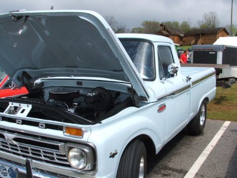 1966 Ford Ranchero - This light blue 1966 Ford F-100 pickup truck is shown with its hood open, revealing the engine bay.