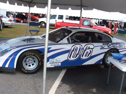 1966 Ford Ranchero - A race car with 'FUSION' and '06' graphics is parked outdoors under a tent.