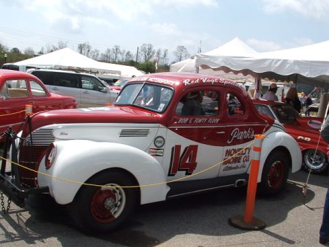 1966 Ford Ranchero - A vintage race car with racing decals and sponsor names is displayed under tents.