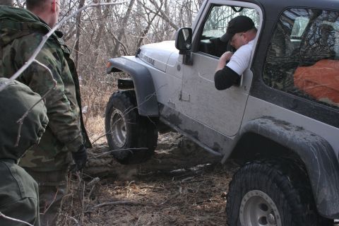 1995 Jeep Cherokee - A silver Jeep Wrangler is stuck in the mud, with several people attempting to help.