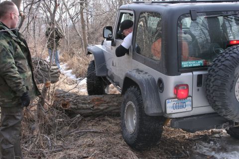1995 Jeep Cherokee - A Jeep Wrangler navigates an off-road obstacle, with a driver and passenger inside.