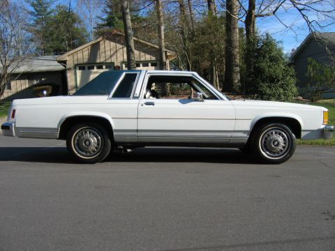 1985 Ford LTD Crown Victoria - This white coupe features a vinyl roof and a side profile that suggests it is a Ford LTD model.