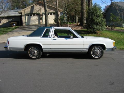 1985 Ford LTD Crown Victoria - Side profile of a white two-door sedan with a dark vinyl roof.