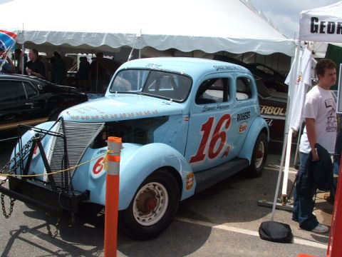1966 Ford Ranchero - A light blue vintage race car, possibly a modified sedan, is displayed outdoors with various sponsorships visible on its body.