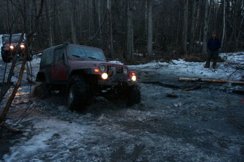 1995 Jeep Cherokee - Two Jeeps navigate a challenging, icy trail in a forest during twilight.