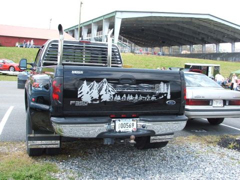 1966 Ford Ranchero - A black Ford F-350 Super Duty pickup truck is parked next to a sedan, with a large decal on its tailgate.