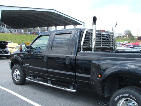 1966 Ford Ranchero - A black pickup truck with large chrome exhaust stacks is parked outdoors near a covered seating area.