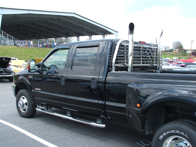 Black pickup truck with dual rear wheels, chrome stacks, and a headache rack