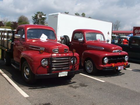 1966 Ford Ranchero - Two classic red Ford trucks are displayed, with the one on the left a wooden flatbed and the one on the right showing custom wheels.