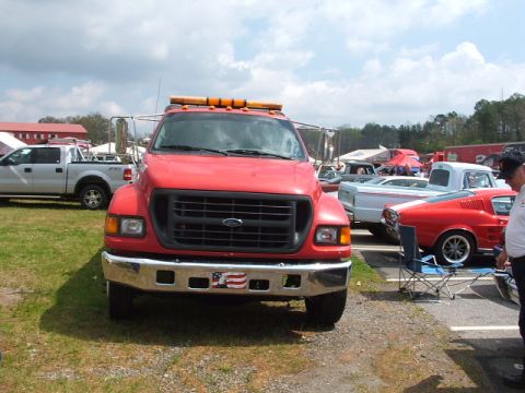 1966 Ford Ranchero - A red tow truck is parked in a lot with several other vehicles around it.
