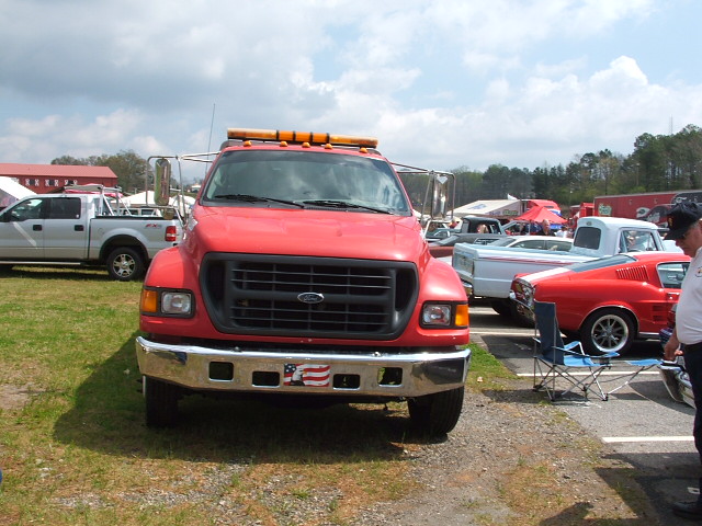 Red tow truck parked outdoors with other vehicles visible in the background
