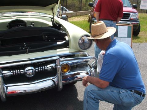 1966 Ford Ranchero - A man inspects the front of a pale yellow vintage car, which appears to be from 1955, not 1966.