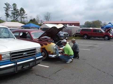 1966 Ford Ranchero - Two men attend to the engine of a maroon sedan adorned with flame decals, parked at an outdoor event.
