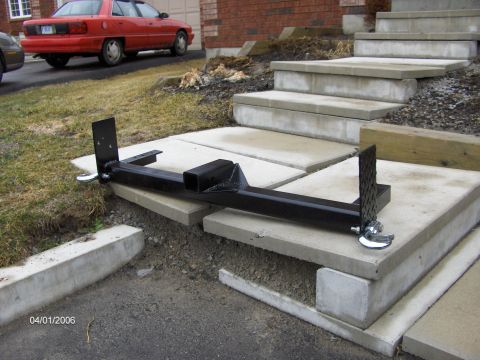 1986 Ford Bronco - Tow hitch receiver and parts are placed on concrete steps, with a red car visible in the background.