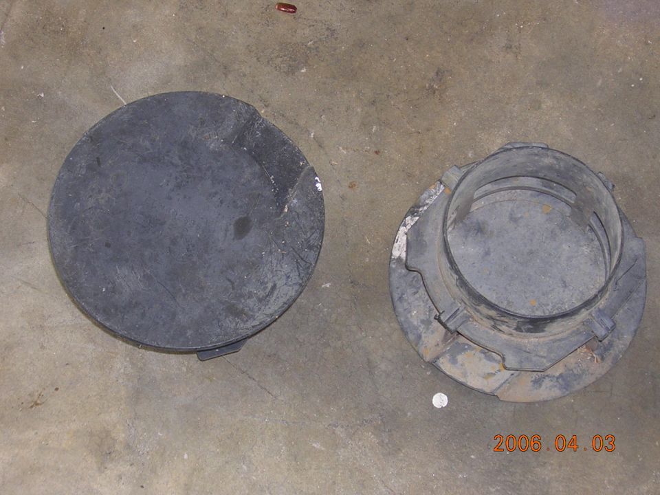 Black round automotive cover and flanged housing part on concrete floor