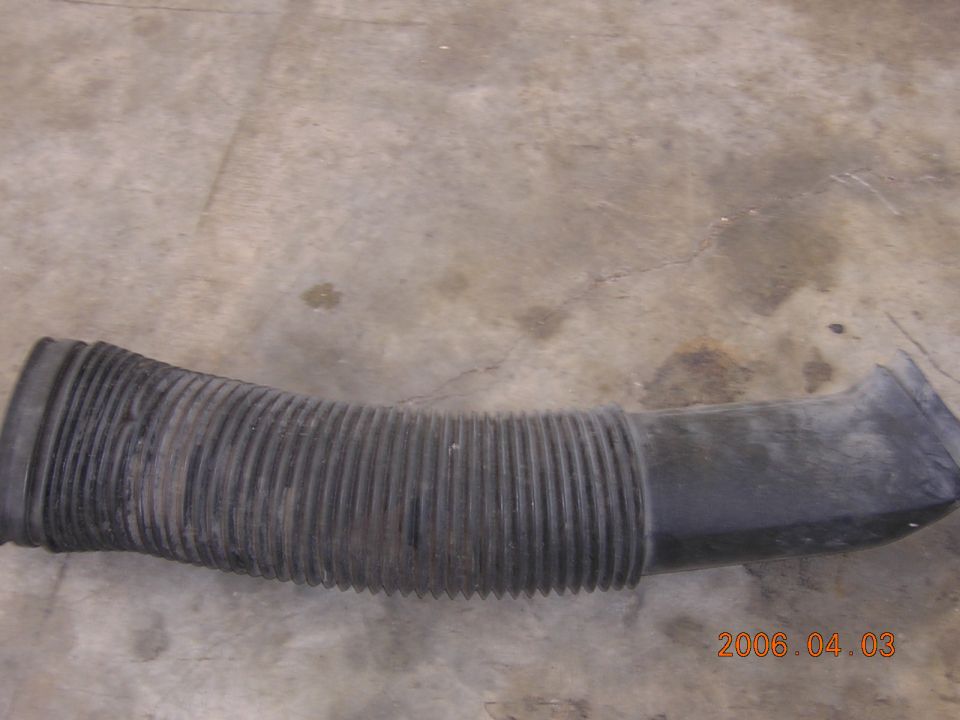 Black ribbed plastic air intake duct lying on concrete floor