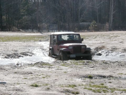 2004 Dodge 2500 - A red Jeep Wrangler navigates a muddy terrain, with "Off Road" visible on the windshield.