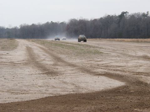 2004 Dodge 2500 - Multiple vehicles travel down a dirt track, kicking up dust under an overcast sky.
