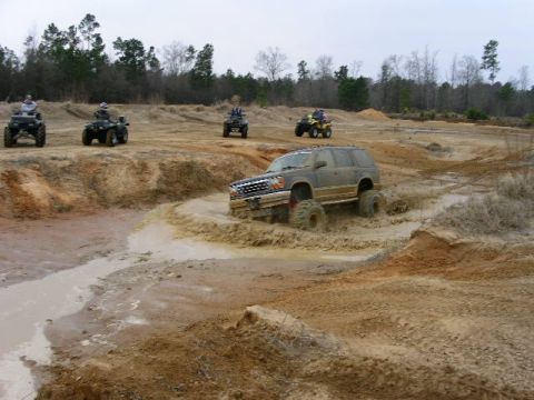 2004 Dodge 2500 - Several ATVs and a lifted SUV navigate a muddy off-road course.
