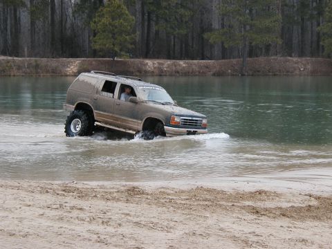 2004 Dodge 2500 - Muddy SUV navigates through a body of water, kicking up spray.