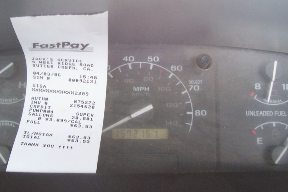 Vehicle dashboard with speedometer and fuel gauge, a receipt from Jack's Service is visible