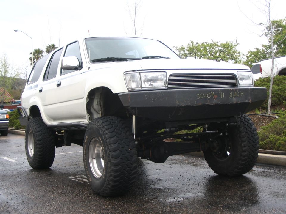 Front three-quarter of a white lifted 4Runner with custom bumper on wet lot