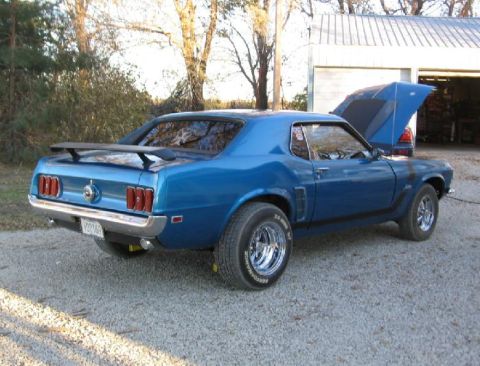 1969 Ford Mustang - This blue 1969 Ford Mustang is parked outside a garage with its hood up.