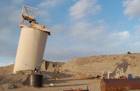 1979 Ford Bronco - A large, leaning silo stands in a desolate area under a partly cloudy sky.